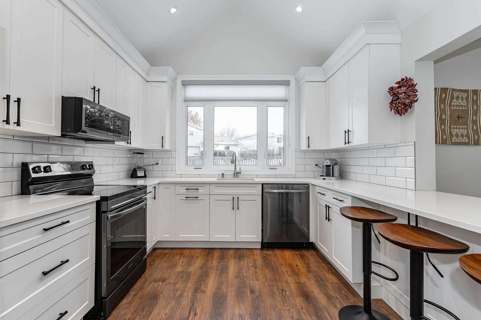 White kitchen with black island, gold pendants and wood floor