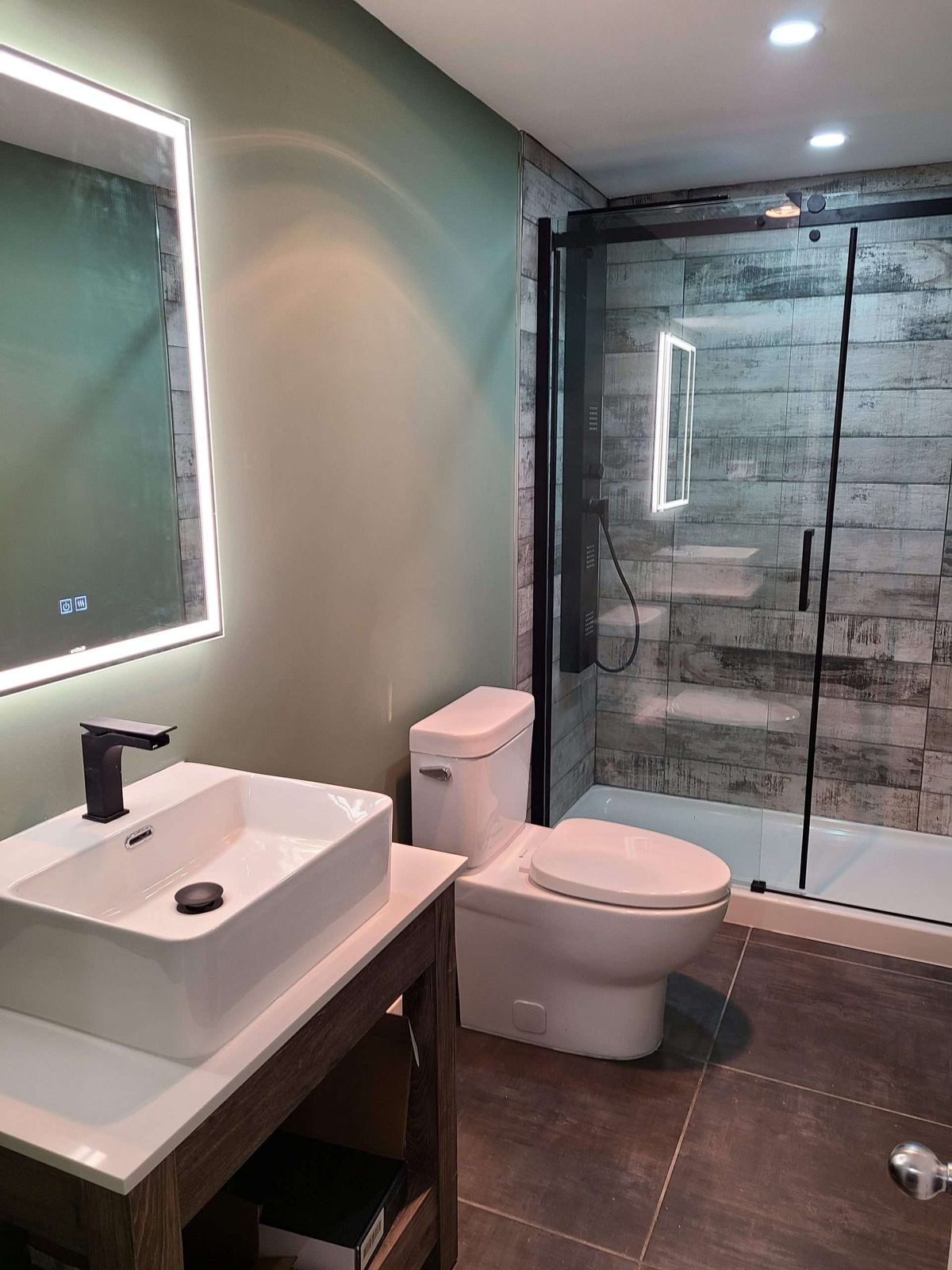 Moody green-wall bathroom with a backlit round mirror