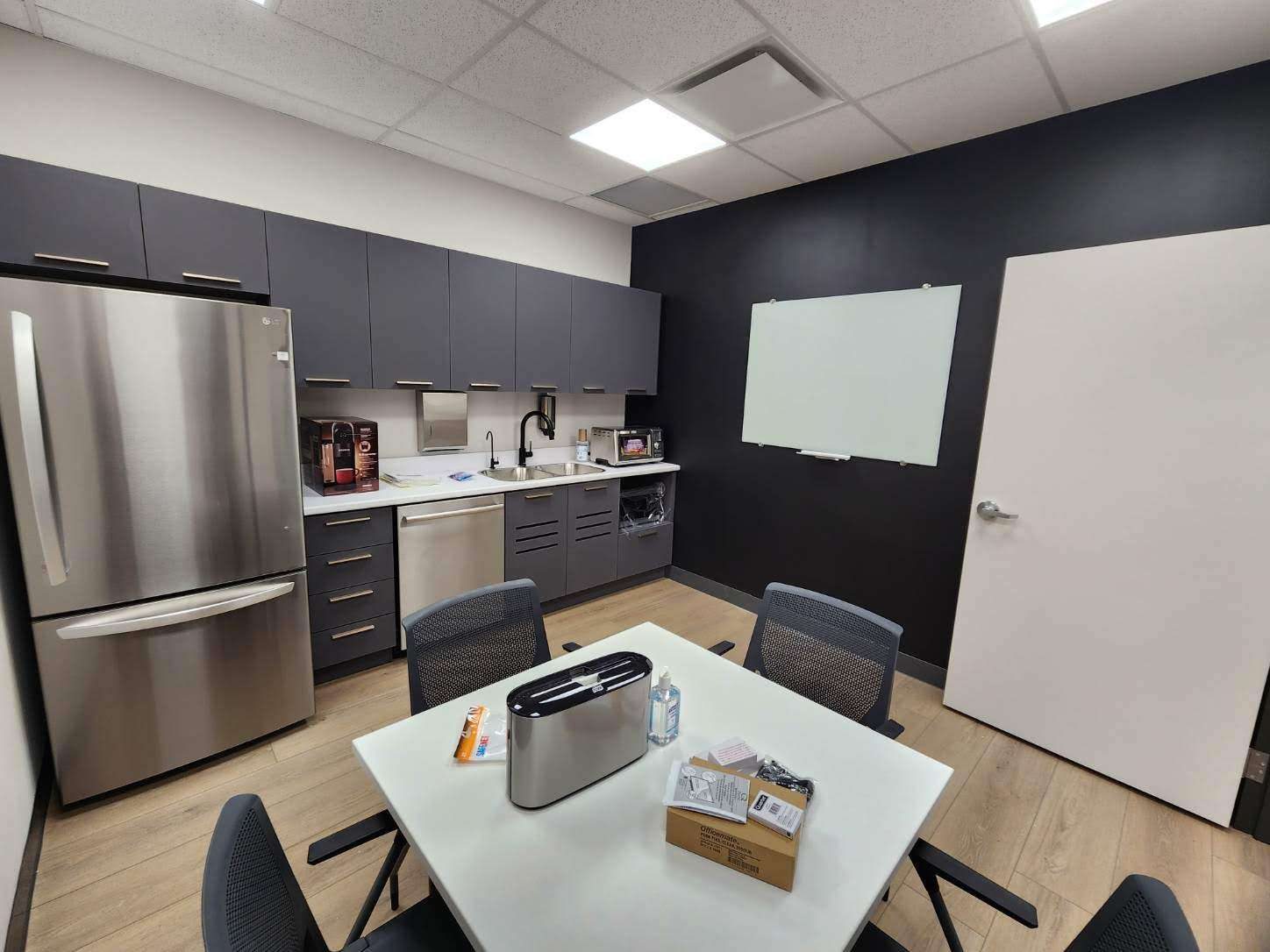 Renovated commercial break room with fridge and dark accent wall